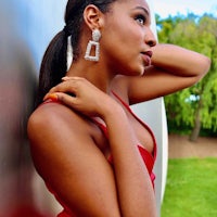 a woman in a red dress leaning against a wall