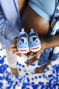 a couple holding blue baby shoes in front of a blue background