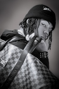 a black and white photo of a man holding a louis vuitton bag